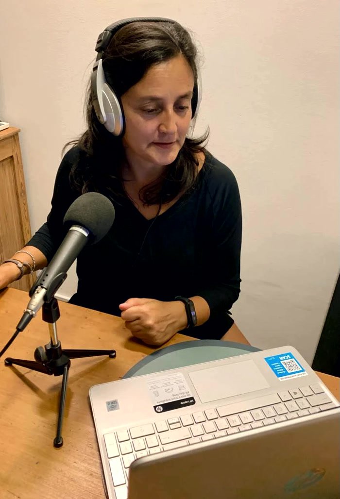 Andrea Cruz con los cascos puestos, leyendo frente al micrófono